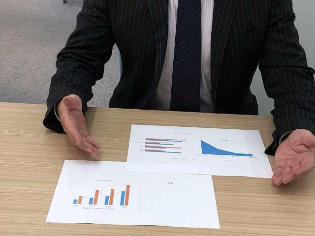 資料を提示して話すビジネスマン